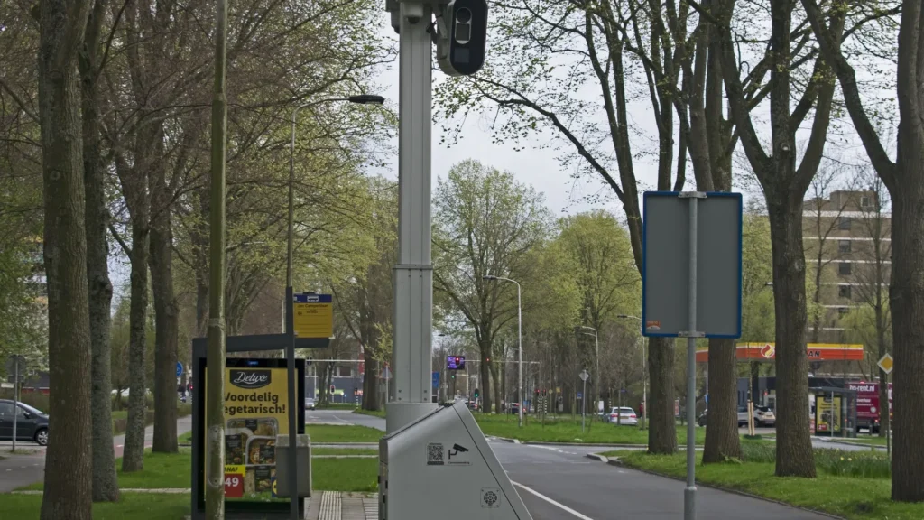 Radar fixe installé le long d’une route urbaine bordée d’arbres