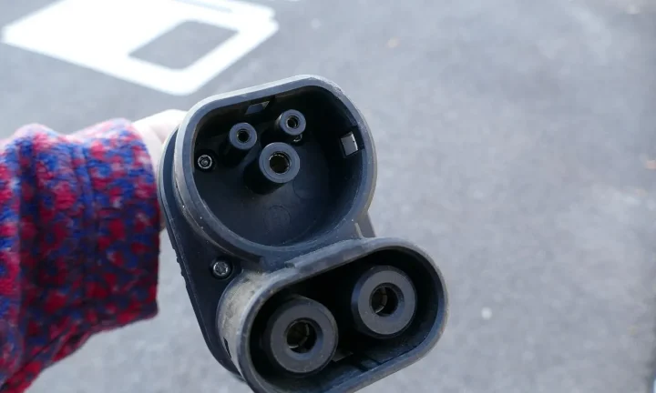 Voiture électrique réelle photographiée près d’une borne de recharge pour « Fin des avantages fiscaux pour les hybrides rechargeables : quel avenir pour les VE ? »
