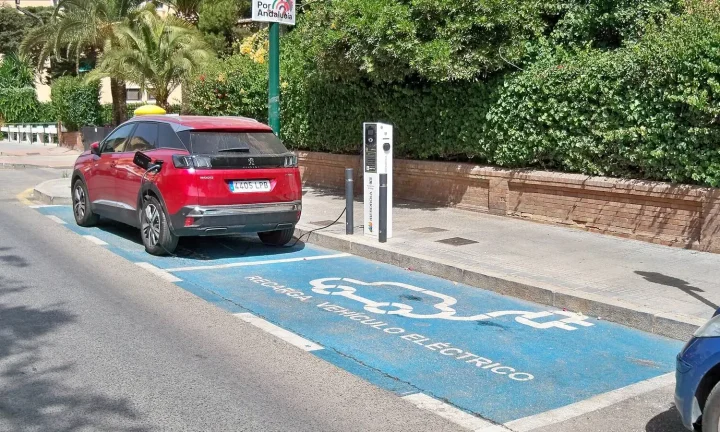 Voiture électrique réelle photographiée près d’une borne de recharge pour « Installer une borne de recharge à domicile en Belgique: Coût, aides et démarches »