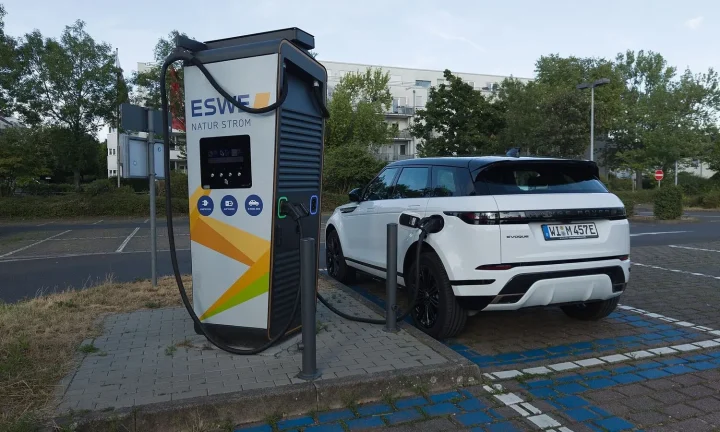 Voiture électrique réelle photographiée près d’une borne de recharge pour « Le Mythe de la ‘Recharge Ultime’ : L’Autonomie Réelle des VE Longue Distance »