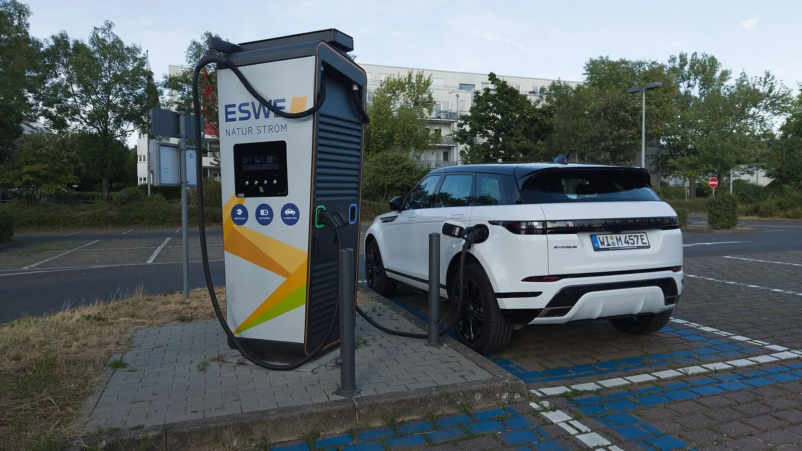 Voiture électrique réelle photographiée près d’une borne de recharge pour « Le Mythe de la ‘Recharge Ultime’ : L’Autonomie Réelle des VE Longue Distance »