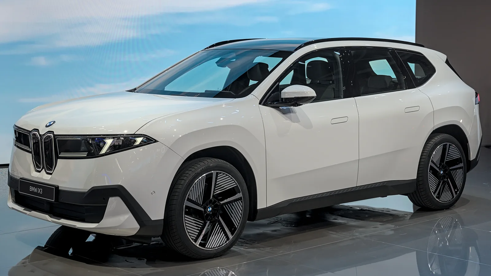 BMW iX3 blanc présenté sur un stand automobile