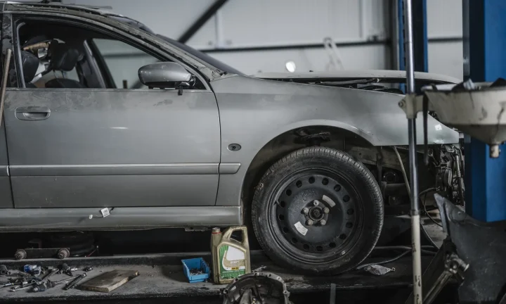 Voiture grise partiellement démontée dans un atelier automobile avec des outils au sol