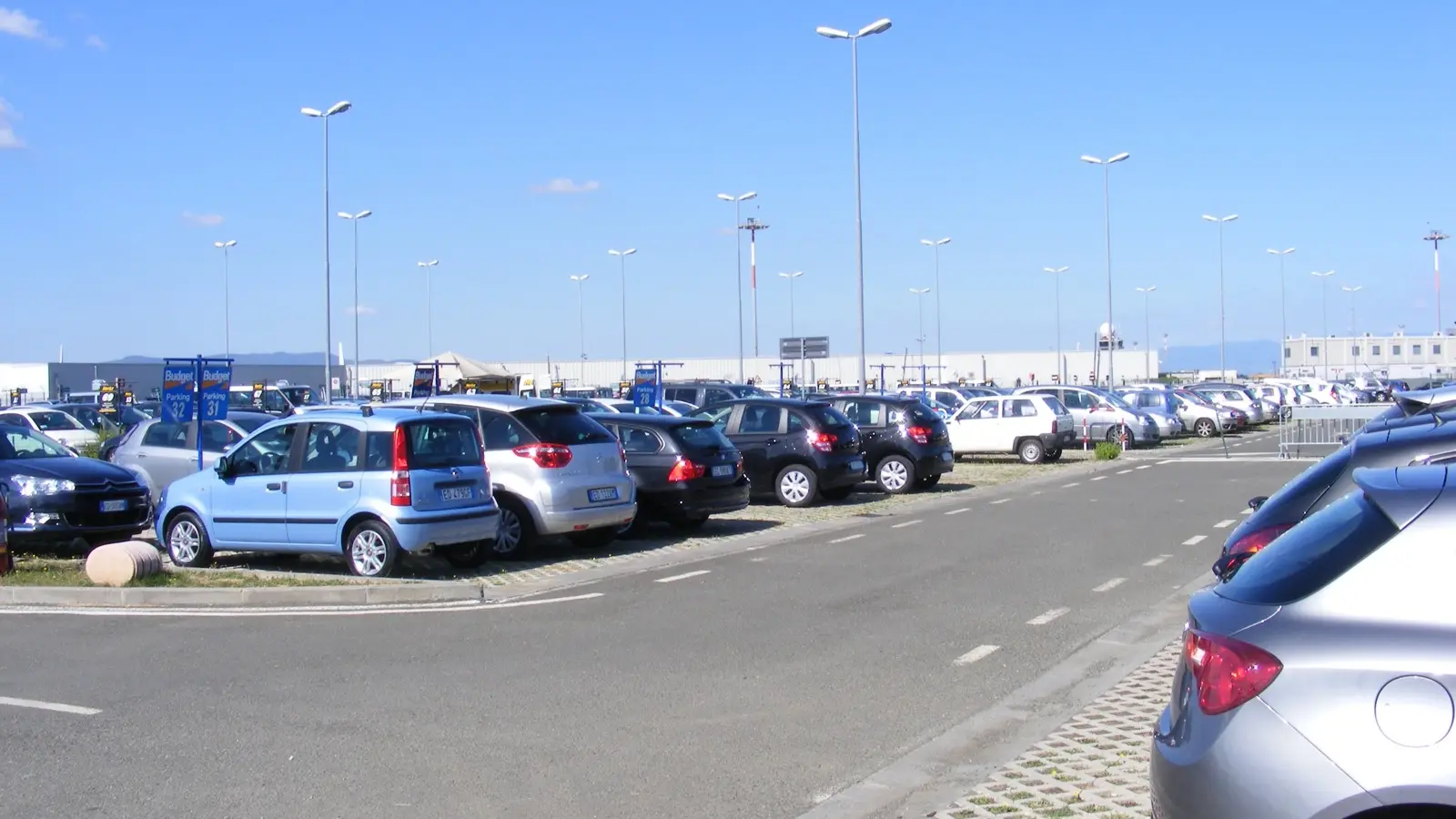 Rangées de voitures de location stationnées sur un parking près d’un aéroport