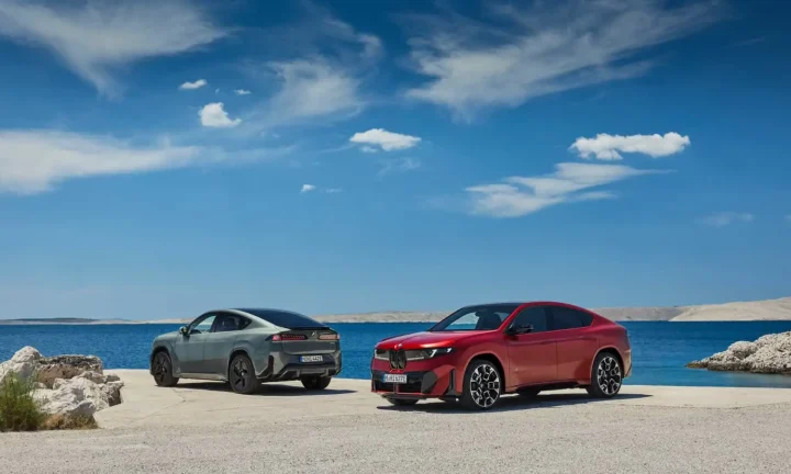 Deux BMW iX4 électriques rouge et grise au bord de la mer