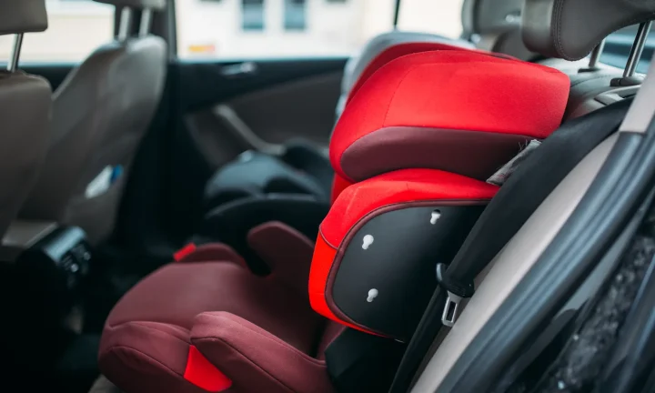 Siège auto rouge pour enfant installé et attaché sur la banquette arrière d’une voiture