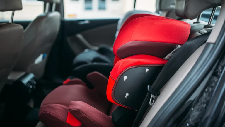 Siège auto rouge pour enfant installé et attaché sur la banquette arrière d’une voiture