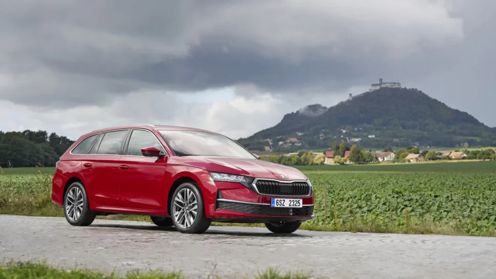 Škoda Octavia rouge photographiée devant un paysage de campagne