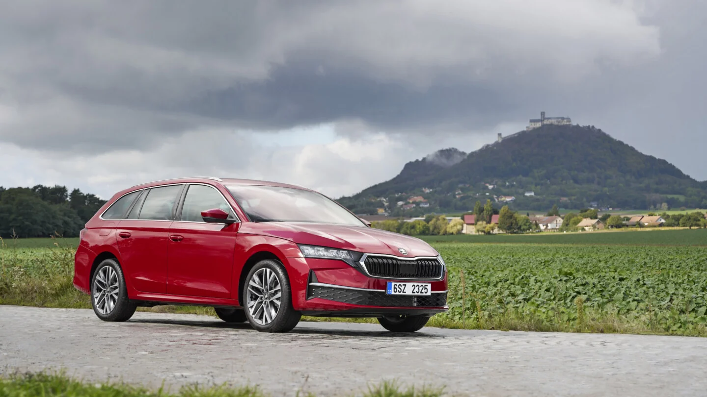 Škoda Octavia rouge photographiée devant un paysage de campagne