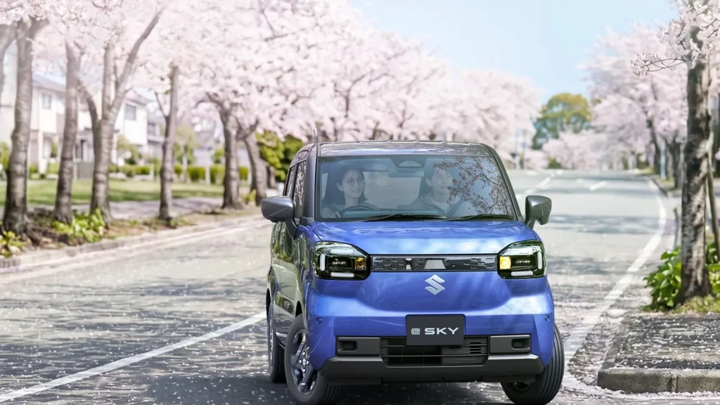 Suzuki e Sky bleue photographiée de face sur une route bordée de cerisiers au Japon